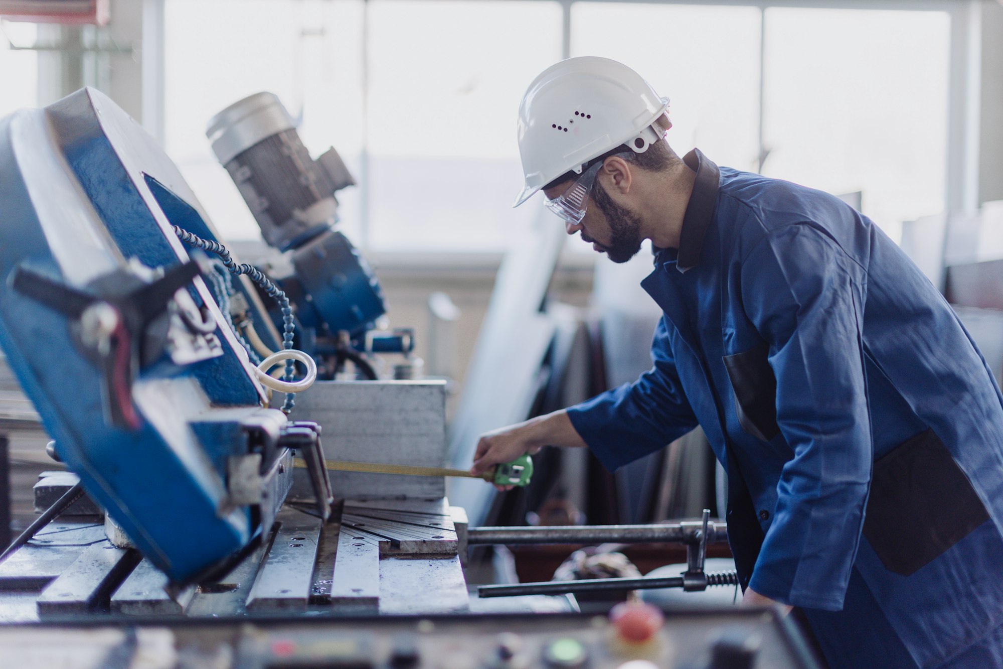 Factory male worker in plant production drilling at metal machine in industrial factory.